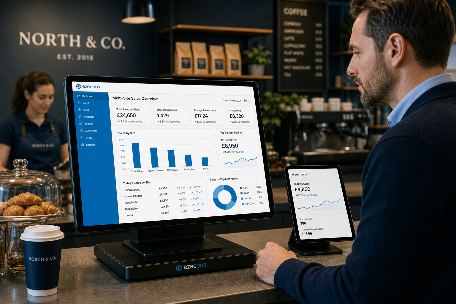Why Multi-Site Reporting Matters for Growing UK Retail and Hospitality Businesses: A photorealistic commercial photography style image set inside a modern UK retail or hospitality business office area with a clean counter and a touchscreen EPOS terminal showing a multi-site sales dashboard with branch comparison charts, daily sales figures and simple blue-accented graphs. A business owner or manager is reviewing the reporting screen beside a coffee shop or small retail counter, with a second screen or tablet visible showing another location's sales summary. Warm natural lighting, shallow depth of field, premium but realistic composition, subtle blue brand accents on the interface and uniforms, professional environment, clear focus on the technology and the practical management of multiple sites, suitable as a WordPress featured image for an ezeepos blog post.
