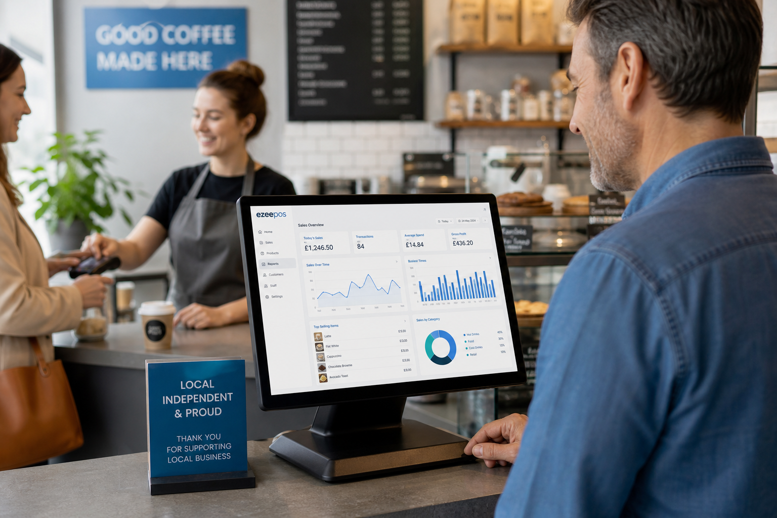 Why Better Reporting Helps Small Businesses Make Smarter Decisions - Photorealistic commercial photography style image for a UK independent café or retail shop, showing a business owner standing beside a clean modern EPOS touchscreen terminal on the counter, reviewing a sales reporting dashboard with simple charts, busiest-time graphs and daily performance figures on the screen, with a staff member serving a customer in the softly blurred background, warm natural daylight, shallow depth of field, premium but realistic composition, subtle blue brand accents on the interface and signage, professional counter area, realistic UK business environment, technology clearly the focus of the image, suitable as a WordPress featured image for ezeepos.
