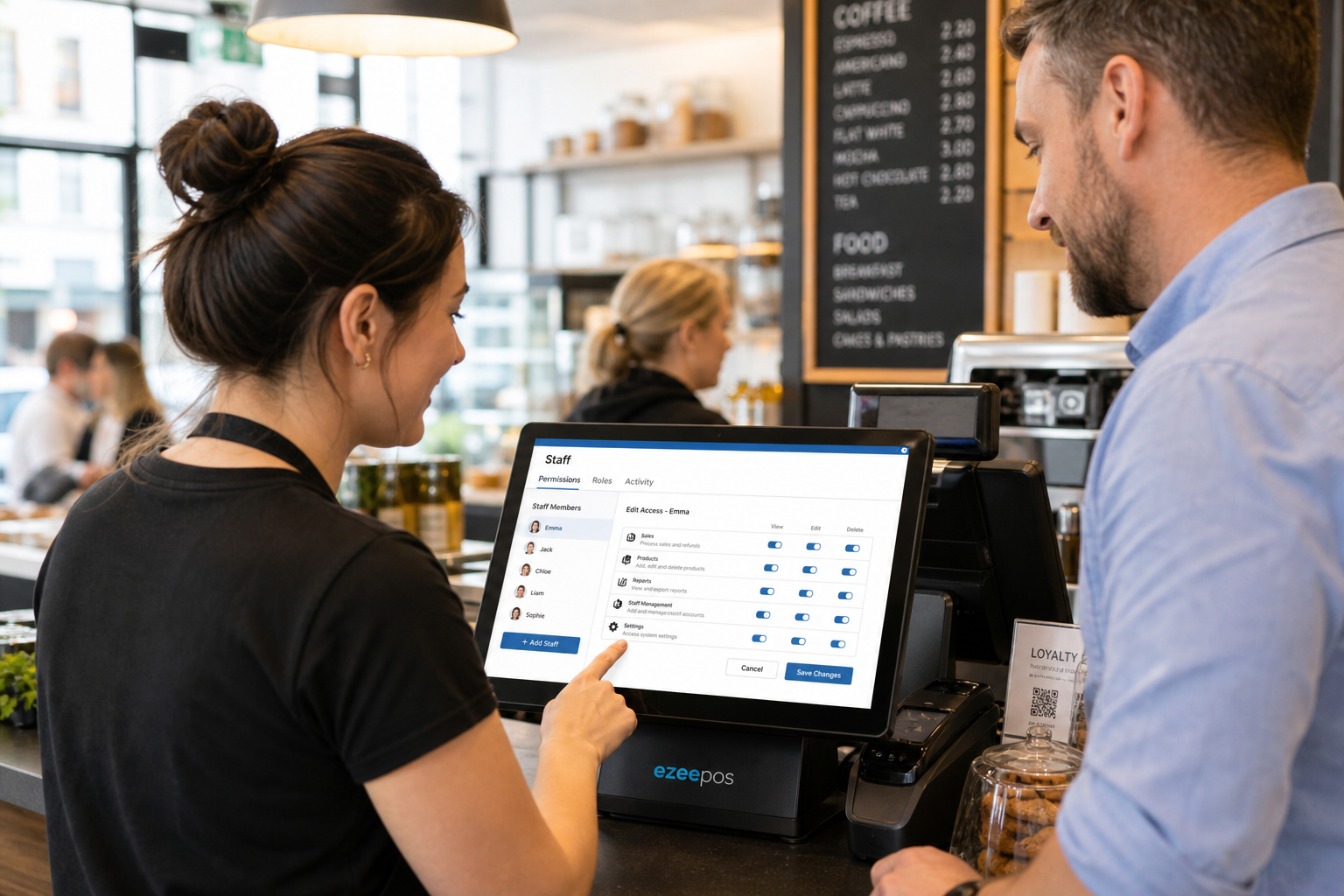 Why Staff Permissions Matter in Busy EPOS Setups, photorealistic commercial photography style showing a modern UK retail or hospitality counter with a touchscreen EPOS terminal displaying a simple staff permissions menu and user access settings, a manager standing beside a team member during a busy service moment, a clean counter with subtle blue interface accents, realistic till setup, calm professional atmosphere, warm natural lighting, shallow depth of field, premium but believable composition, friendly staff interaction, clear focus on the EPOS screen and access control features, suitable as a WordPress featured image for ezeepos, modern independent UK business setting, no clutter, no illustrations, no futuristic elements
