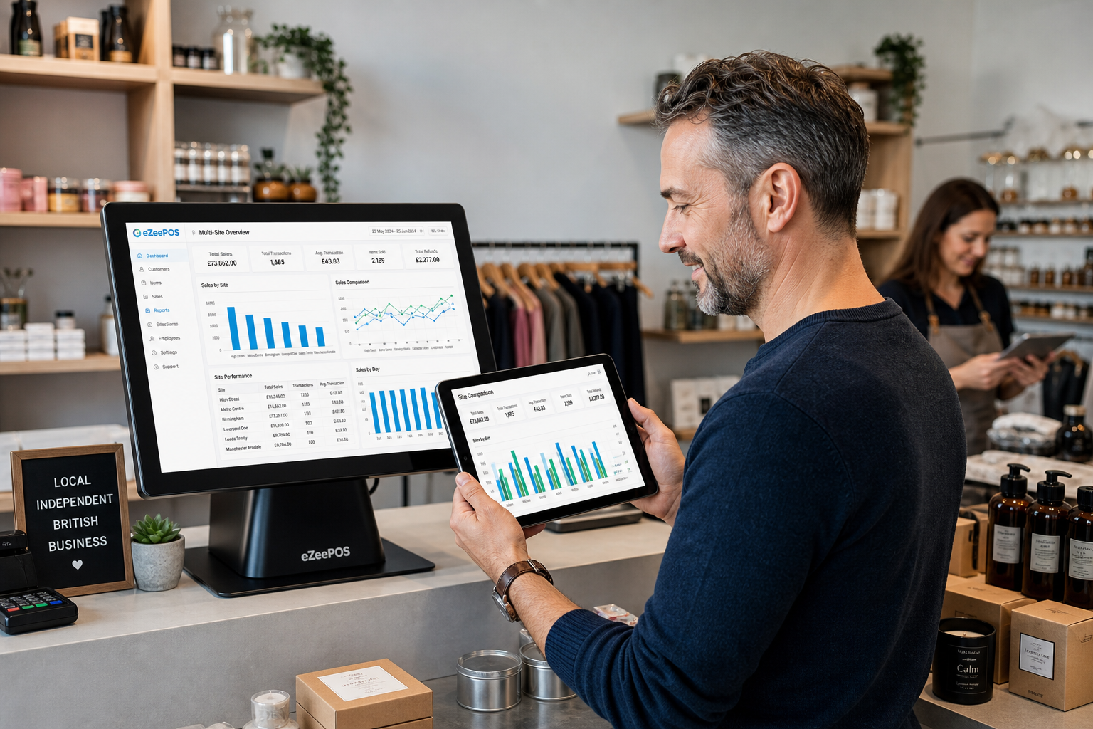 Why Multi-Site Reporting Matters for Growing UK Retail Chains, photorealistic commercial photography style image of a modern UK independent retail business owner reviewing multi-site sales dashboards on an eZeePOS touchscreen POS terminal and tablet at a clean shop counter, with a second branch manager in the background and subtle blue interface accents showing charts, site comparisons and daily totals, realistic retail products displayed neatly around the counter, warm natural lighting, shallow depth of field, premium but believable business environment, professional cheerful mood, technology as the clear focus, suitable as a WordPress featured image for an EPOS blog article about comparing branch performance and making better decisions across multiple retail locations